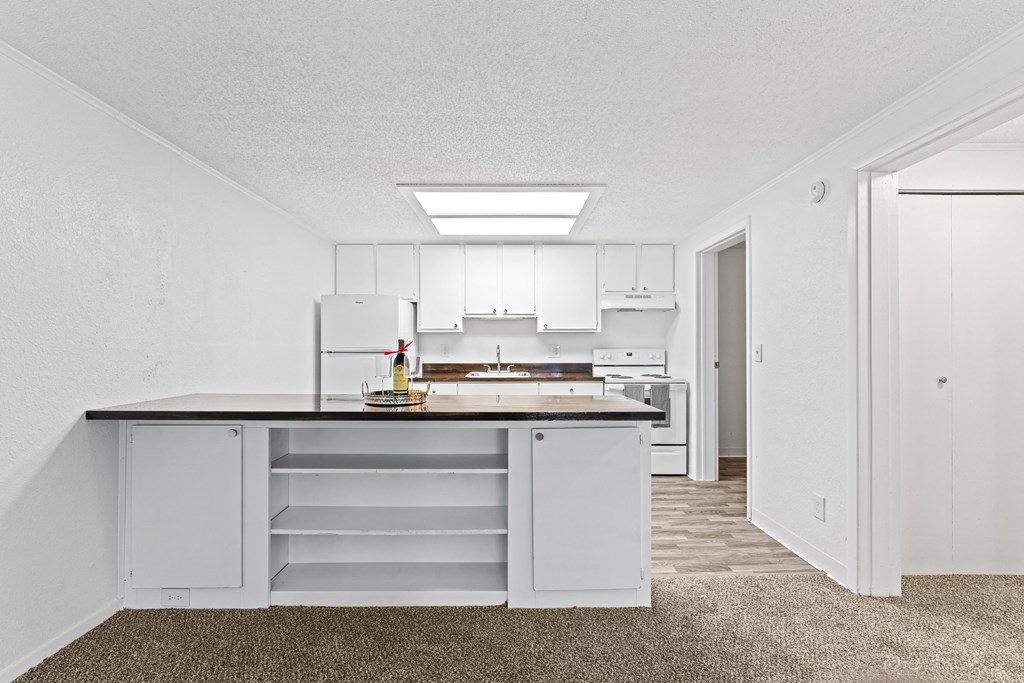a white kitchen with white cabinets and a black counter top