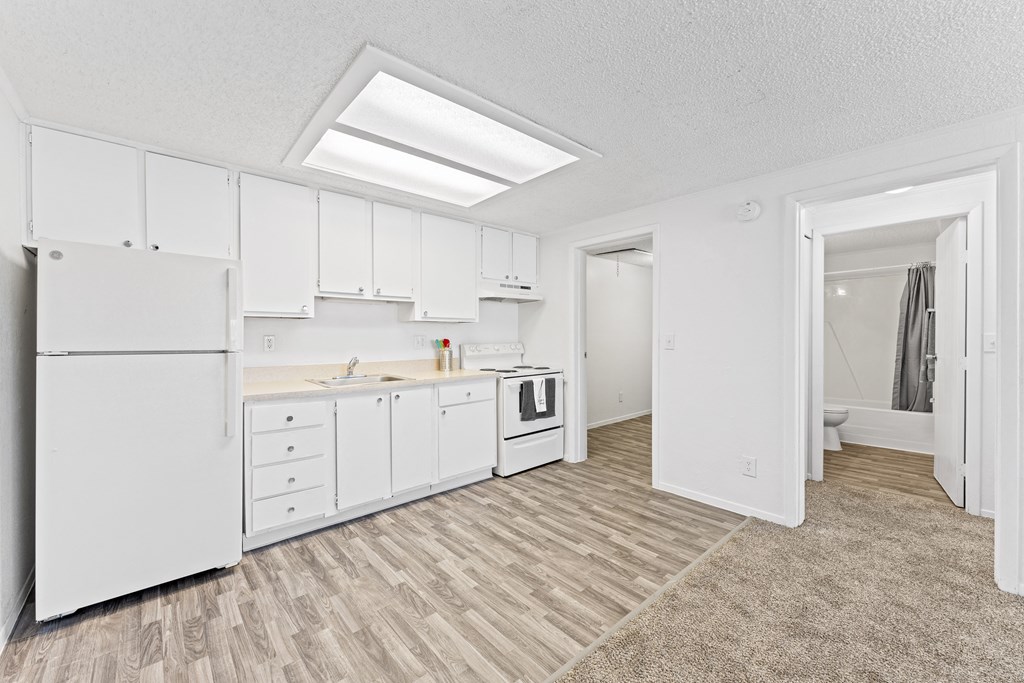 a white kitchen with white cabinets and a white refrigerator