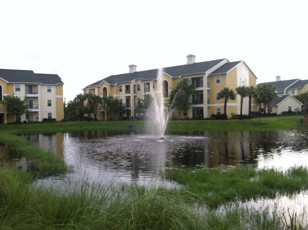 a fountain in the pond in front of an apartment building