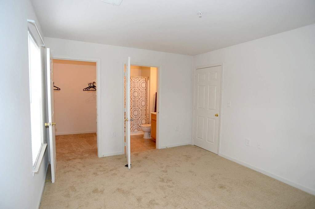 a bedroom with a door to a bathroom and a closet