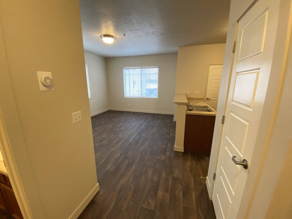 an empty living room and kitchen with wood flooring