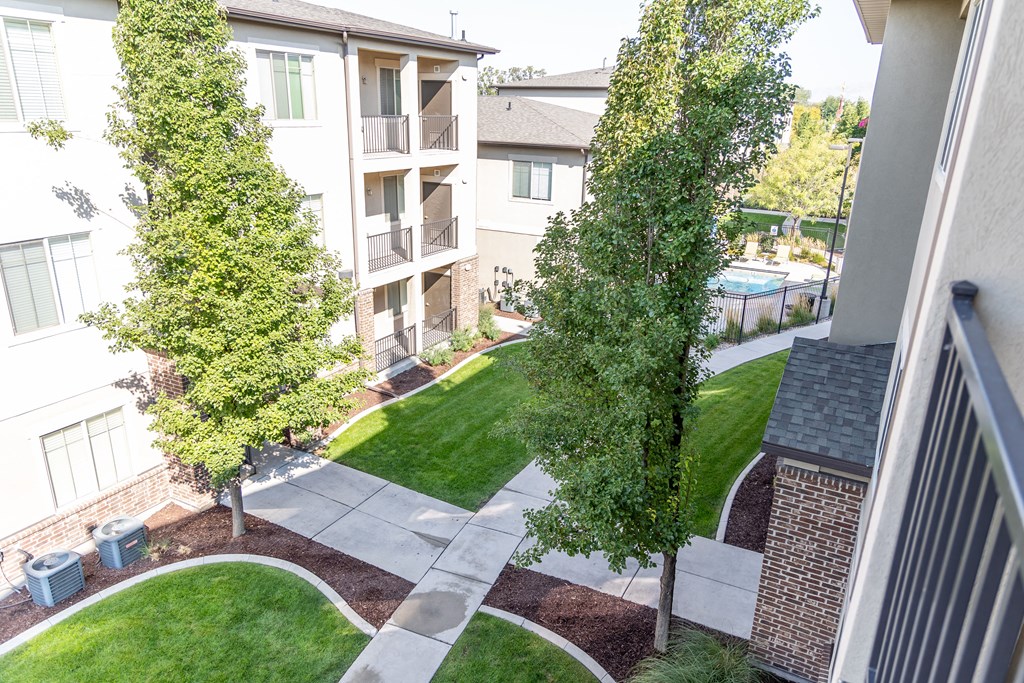 a view of the yard of an apartment building with grass and trees