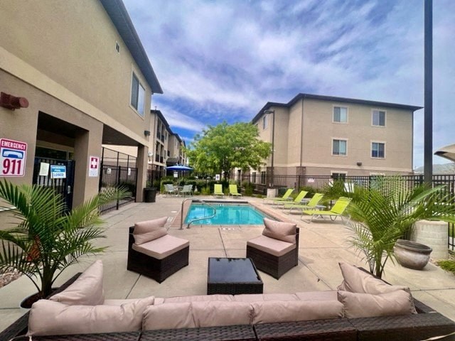 a swimming pool is next to a patio with furniture