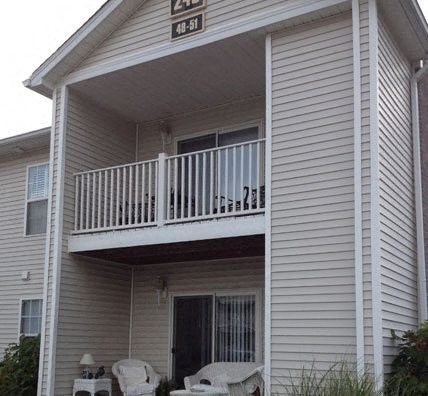 a white house with a balcony and chairs