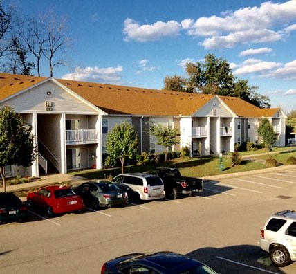 a parking lot filled with cars in front of apartments