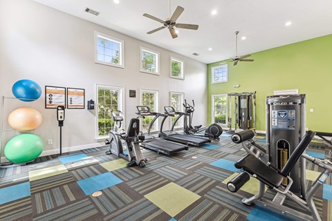 A gym with a variety of equipment including treadmills, exercise balls, and weights.