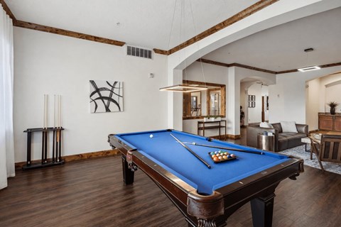 A pool table is in the middle of a room with a blue cloth.