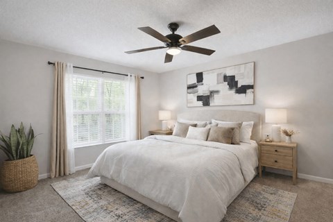 A bedroom with a large bed, a ceiling fan, and a plant.