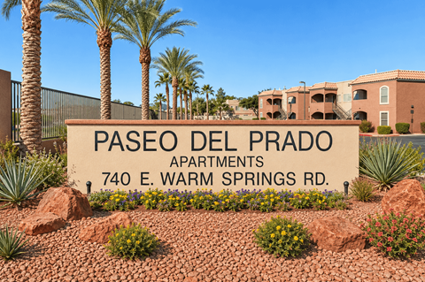 A sign for Paseo Del Prado Apartments stands in front of a building.