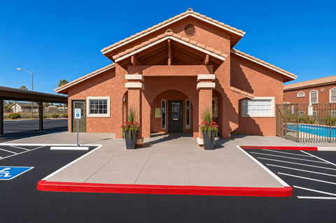 A building with a red roof and a parking lot in front.