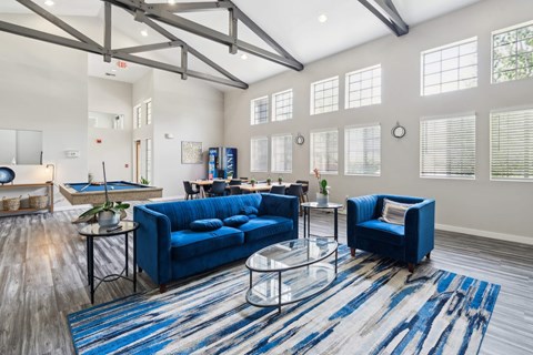 A living room with a blue couch and a glass coffee table.