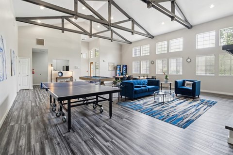 A spacious room with a ping pong table and blue furniture.