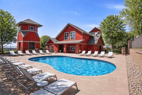 A red house with a pool in front.