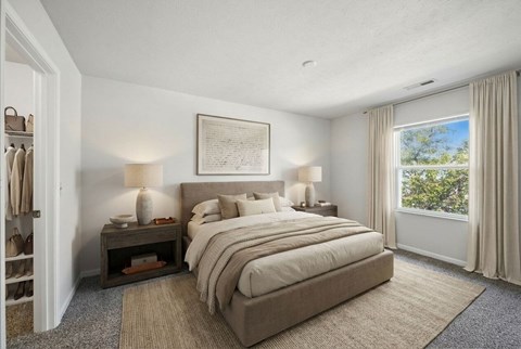 A bedroom with a large bed and a window overlooking trees.