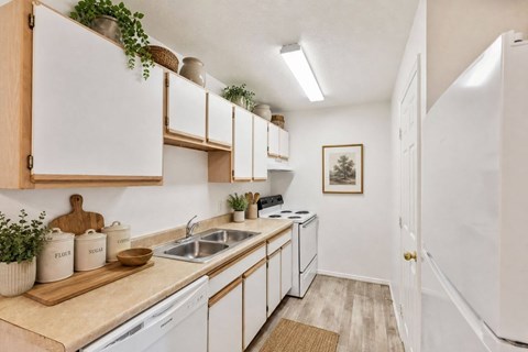 A kitchen with white cabinets and a wooden cutting board on the counter.