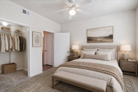 A bedroom with a large bed and a closet with clothes hanging.