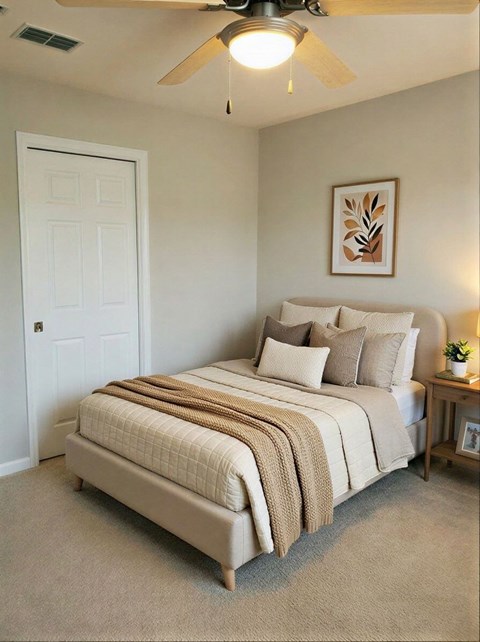 A bedroom with a bed, a ceiling fan, and a nightstand with a plant on it.