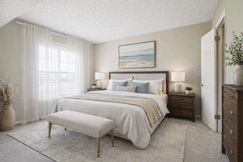 A bedroom with a large bed, a bench, and a painting on the wall.
