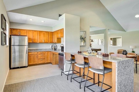 A kitchen with wooden cabinets and a stainless steel refrigerator.