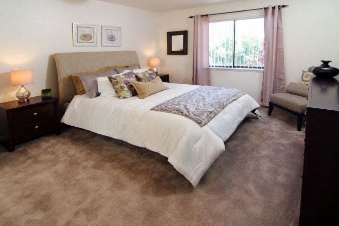 a bedroom with a bed and a chair and a window