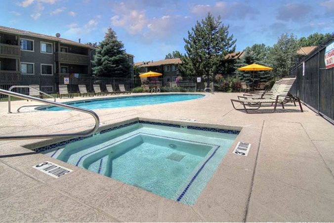 a swimming pool with chairs and umbrellas next to a building