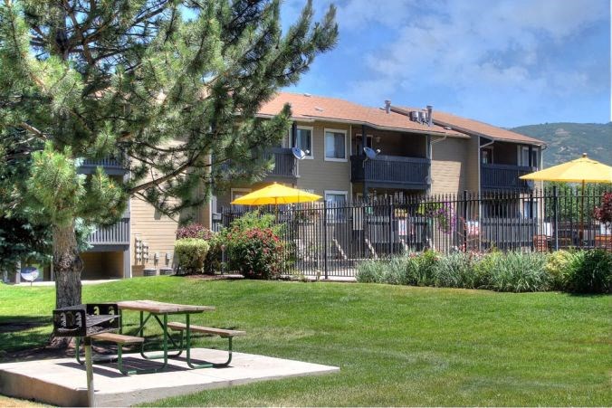 an apartment building with a picnic table and umbrellas