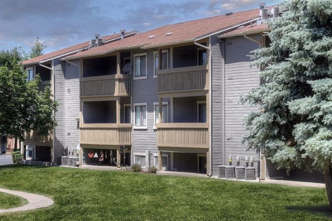 an apartment building with a grass yard and trees