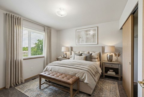 A bedroom with a large bed and a window with curtains.