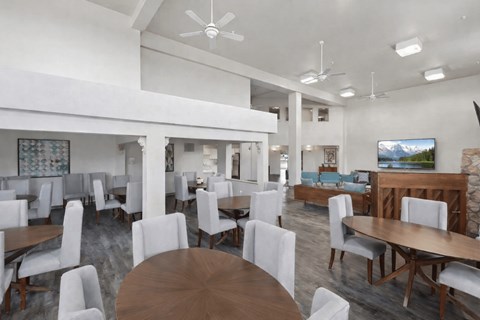 A modern dining room with white chairs and wooden tables.