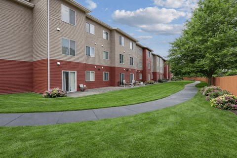 A long building with a red and beige exterior with a green lawn in front.