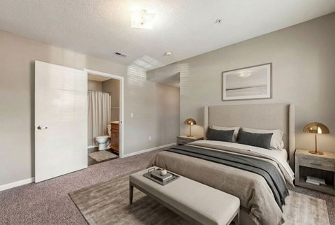 A bedroom with a large bed and a bench in front of it.