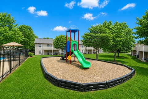 A playground with a green slide and a red and blue structure.