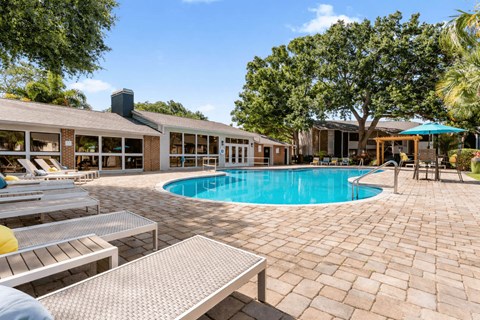 A pool area with sun loungers and a building in the background.