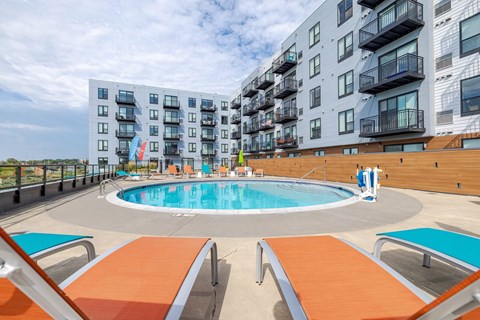 Rooftop pool deck with lounge seating and balconies at Hello Apartments, Minnesota