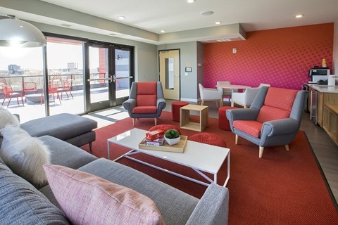 A living room with a grey couch and red chairs.