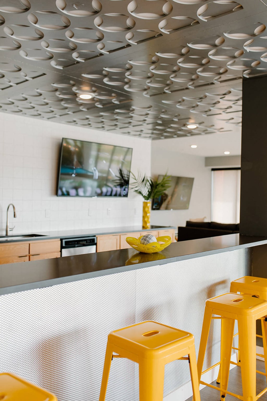 A kitchen with a white counter and yellow stools. at Hello Apartments, Minneapolis, 55427