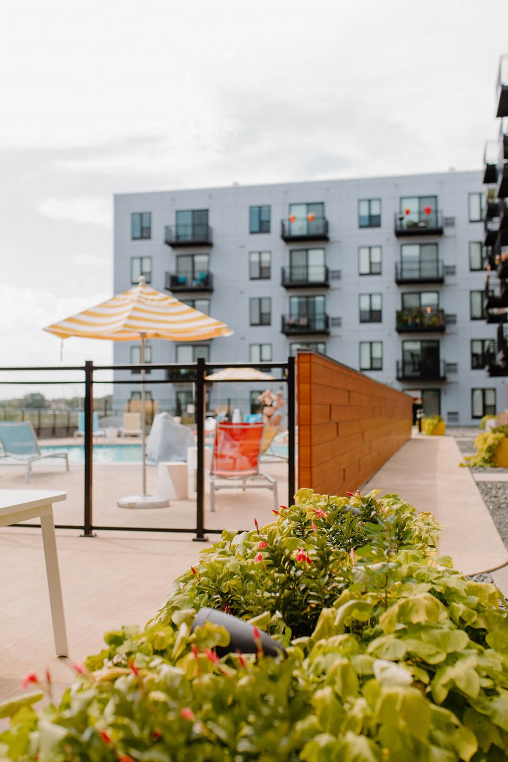 A patio with a striped umbrella and chairs is in front of a building. at Hello Apartments, Minneapolis