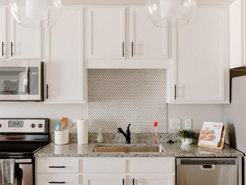 A kitchen with white cabinets and a black stove top oven. at Hello Apartments, Minneapolis