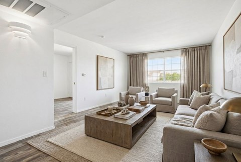 A modern living room with a grey sofa, a wooden coffee table, and a large painting on the wall.