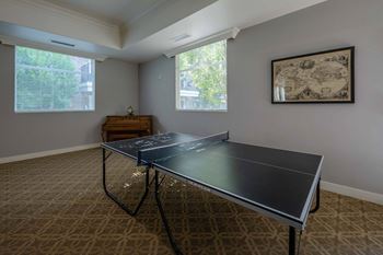 a ping pong table in a room with two windows