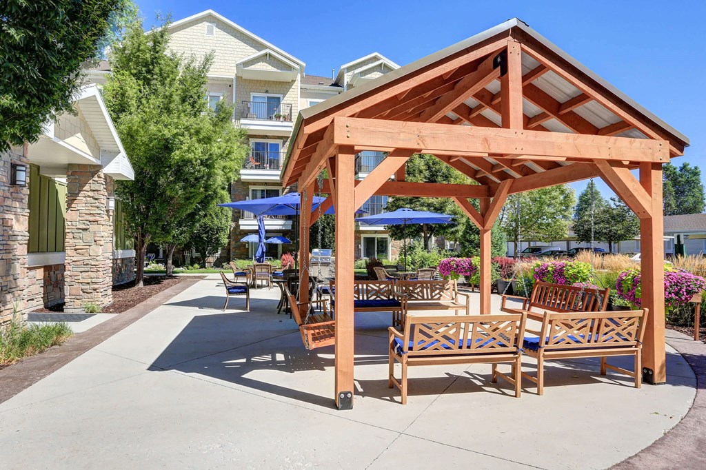 an outdoor patio with wooden furniture and umbrellas at The Beckstead, South Jordan
