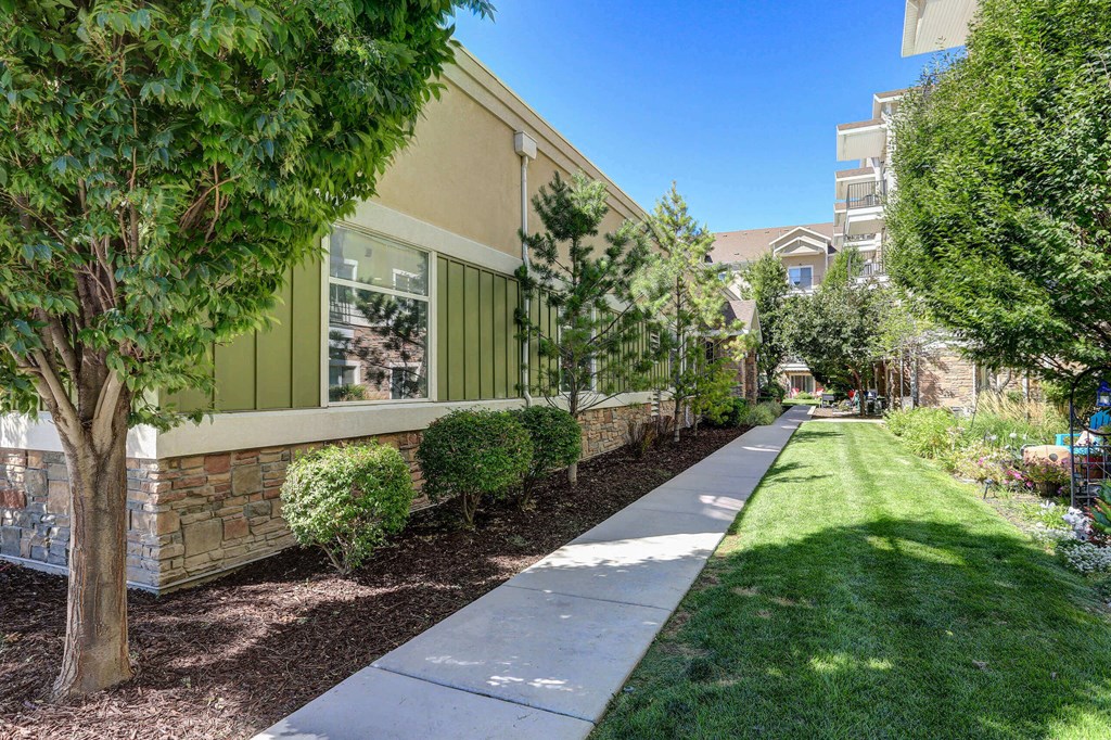 a walkway with trees and bushes in front of a building a walkway with trees and bushes in front of a building at The Beckstead, South Jordan, Utah