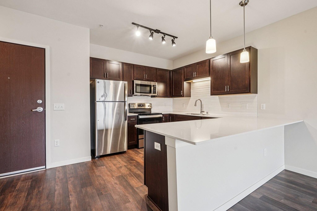 A kitchen with dark wood floors and white countertops. at Aster Meadow, Vadnais Heights, MN