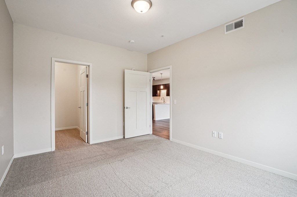 A white room with a carpeted floor and two open doors.at Aster Meadow, Vadnais Heights, MN