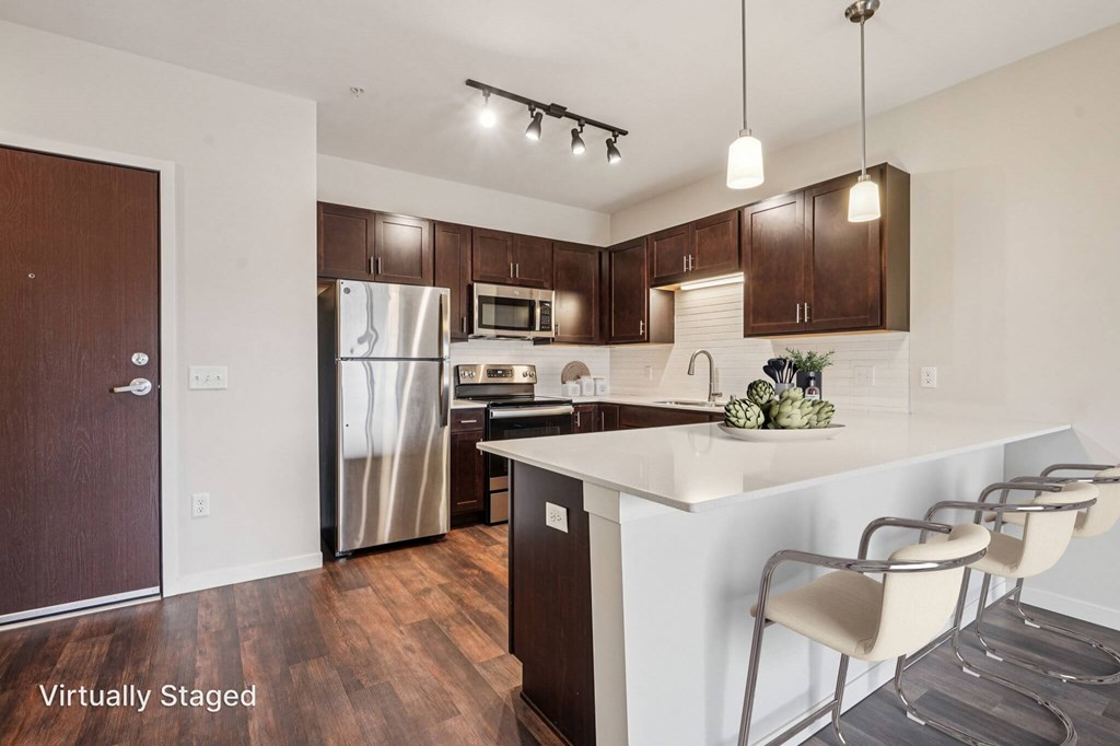 A kitchen with brown cabinets and a white island. at Aster Meadow, Vadnais Heights, MN