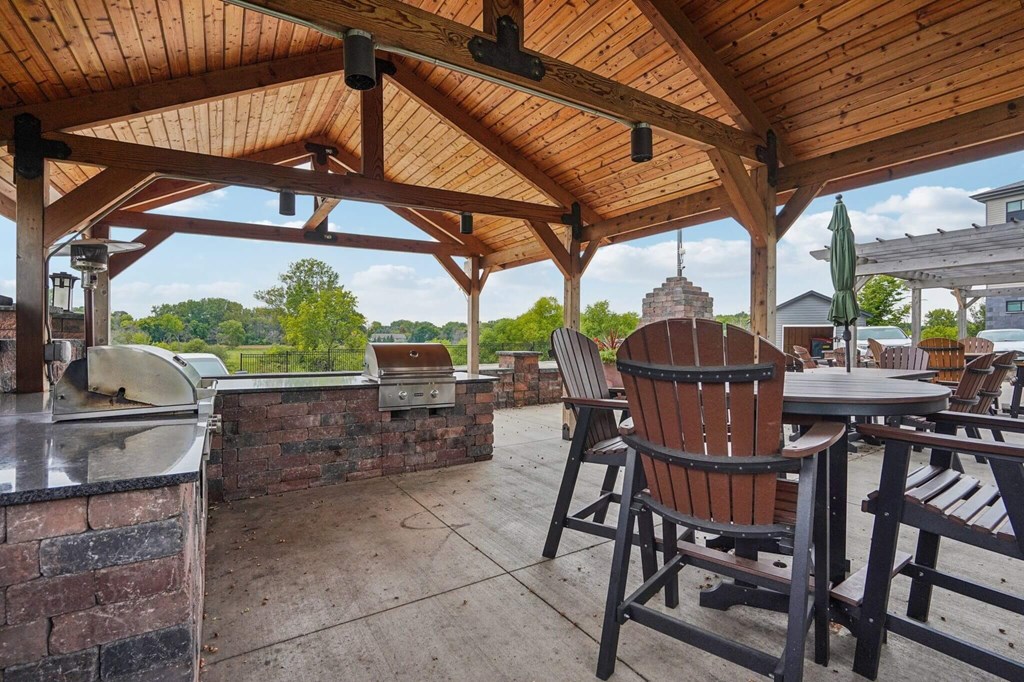 A wooden patio with a grill and chairs. at Aster Meadow, Vadnais Heights, MN