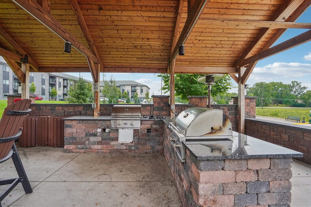 A covered outdoor kitchen area with a grill and seating area. at Aster Meadow, Vadnais Heights, 55127