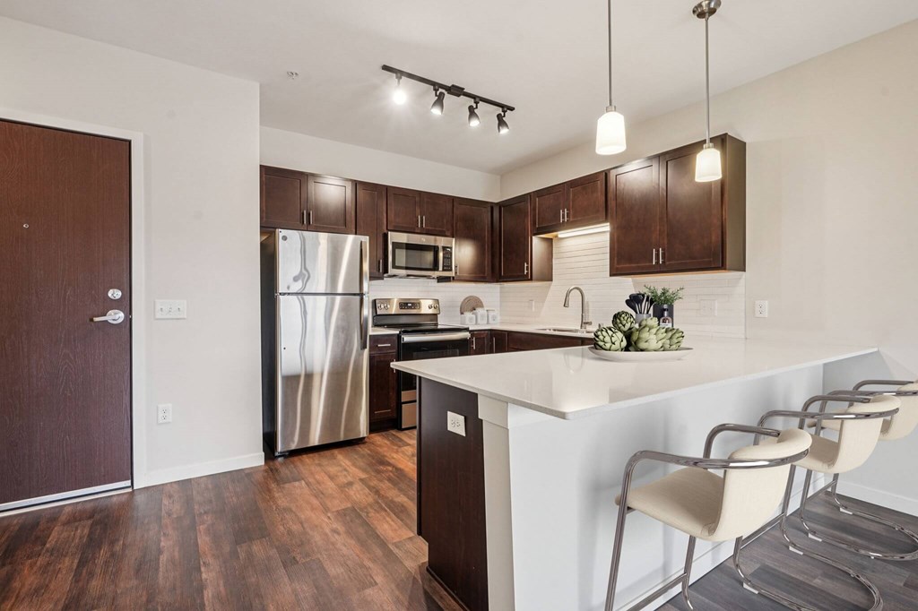 A kitchen with a white counter top and brown cabinets. at Aster Meadow, Vadnais Heights, MN