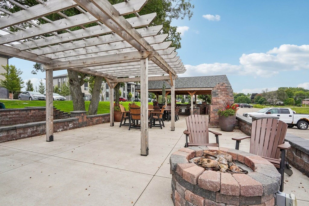 A patio with a fire pit and chairs under a wooden pergola. at Aster Meadow, Minnesota, 55127