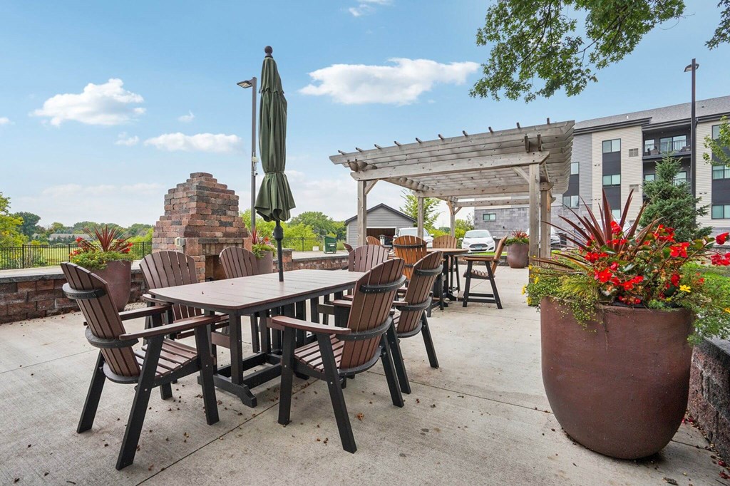 A patio with a table and chairs and a fireplace. at Aster Meadow, Vadnais Heights, MN, 55127